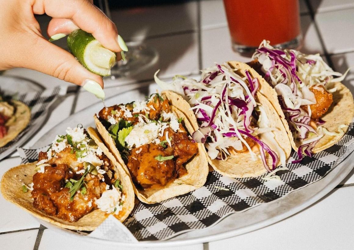 A woman squeezes lime juice over a tray of tacos at mexican joint El Grotto in Scarborough