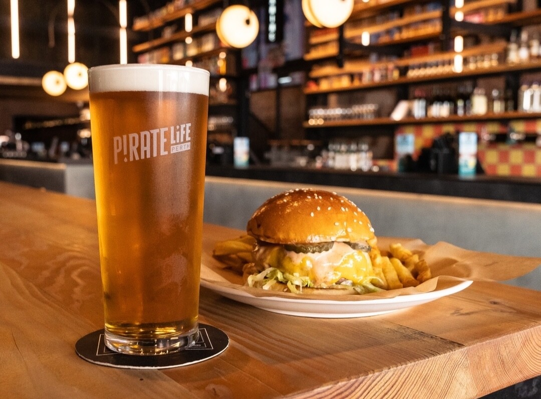 A pint of craft beer and a burger sits on a wooden table at Pirate Life brewery in Perth. 