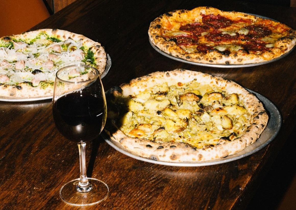 Pizzas and a glass of wine on a table at Bungalow, a restaurant in Dunsborough