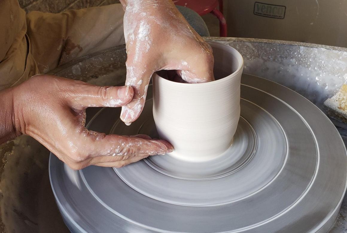 A woman making a cup on a wheel out of pottery at Claymake Studios. One of Perth's best beginner pottery workshops