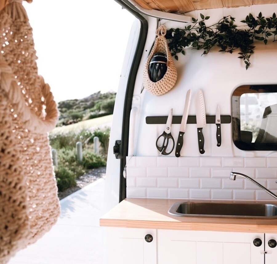 The kitchen inside Wilbur the campervan. Showcasing a sink, wooden tops and knives. This is one of the best campervans to hire in Western Australia (WA).