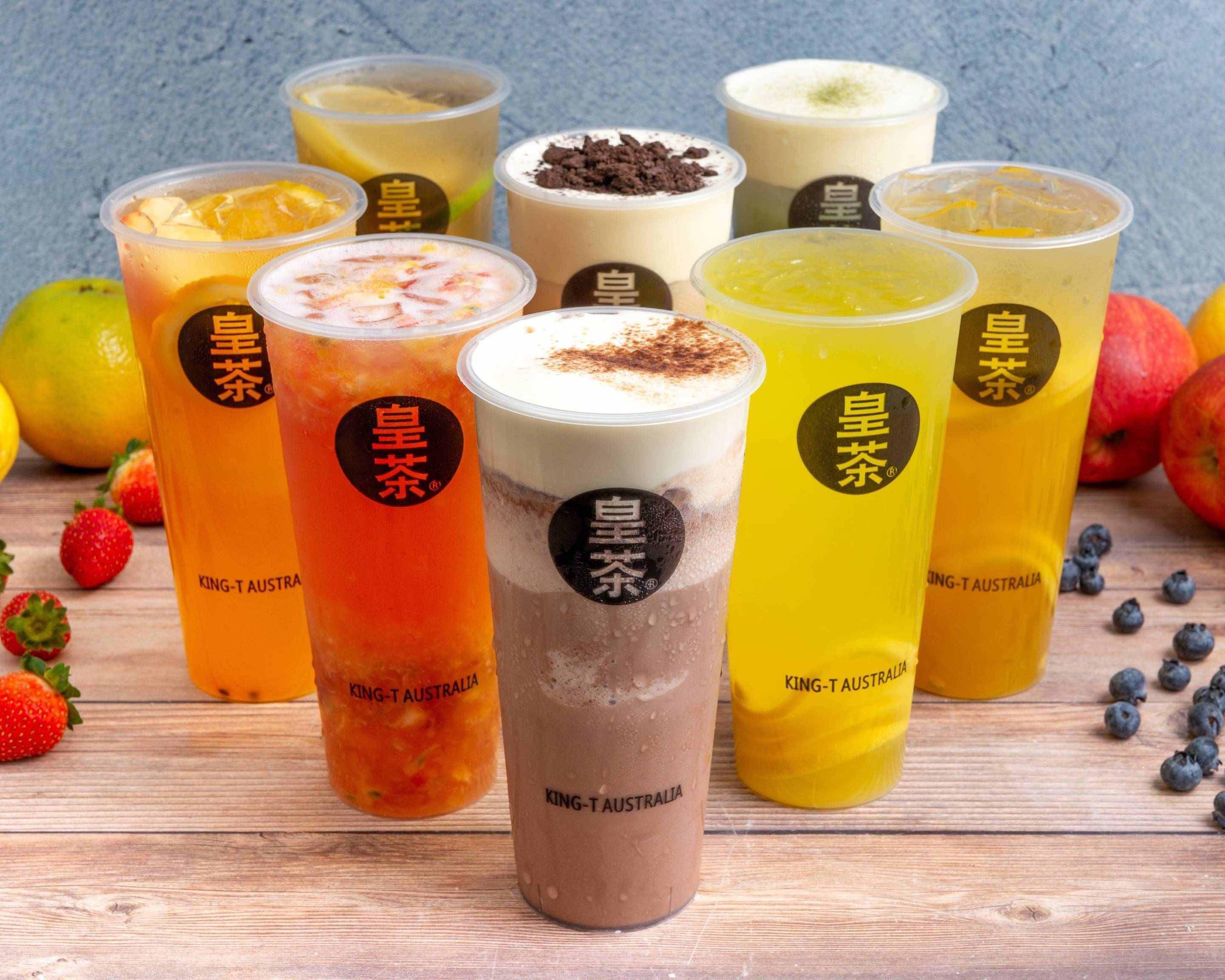 A set of eight different bubble teas sit on a bench at King Tea