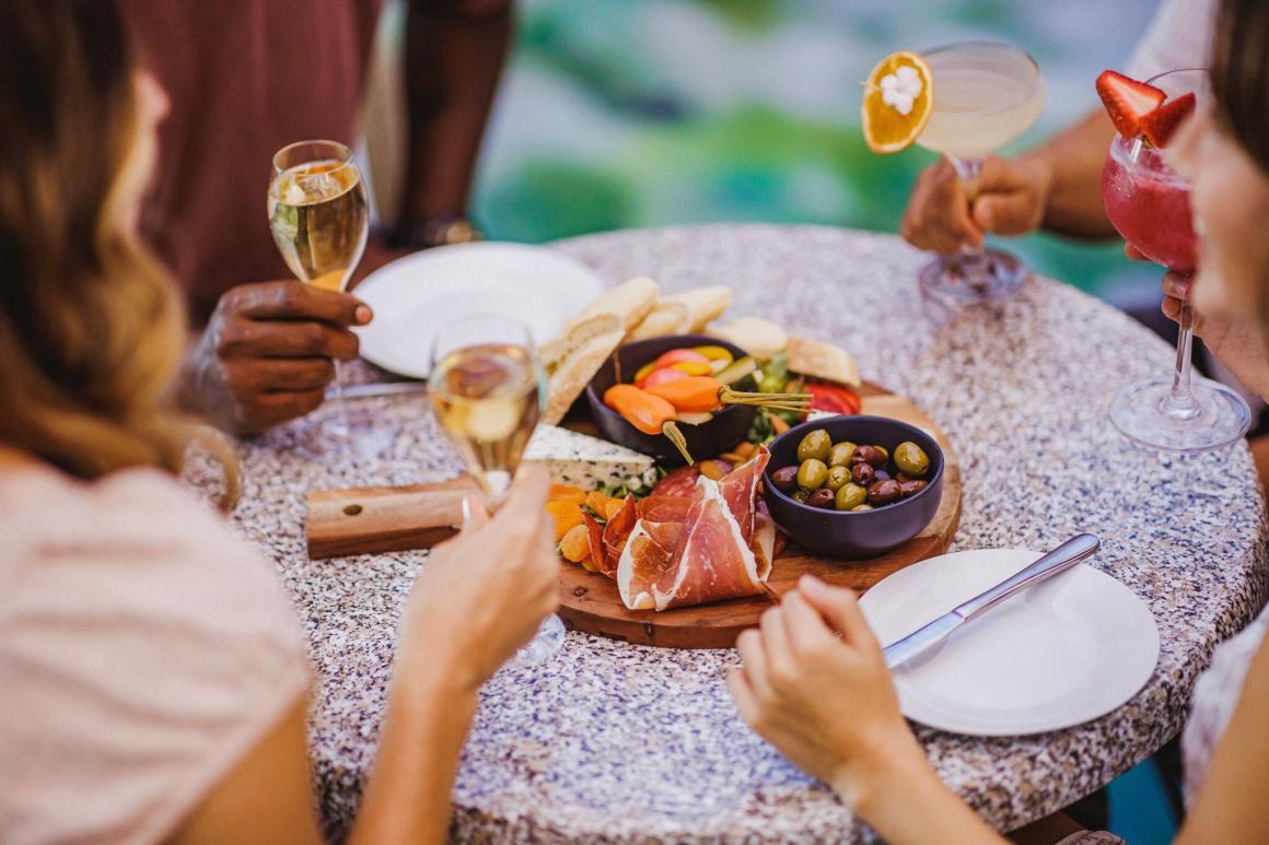 A side view of a table with charcuterie items on it and four people seated around enjoyed cocktails at Monet in Paris