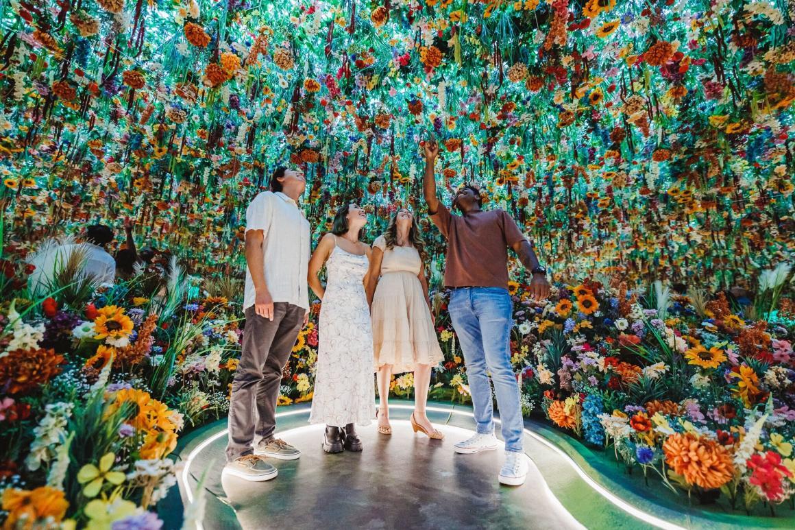 Four people stand in the middle of a huge photo op with flowers hanging from the ceiling at Monet in Paris