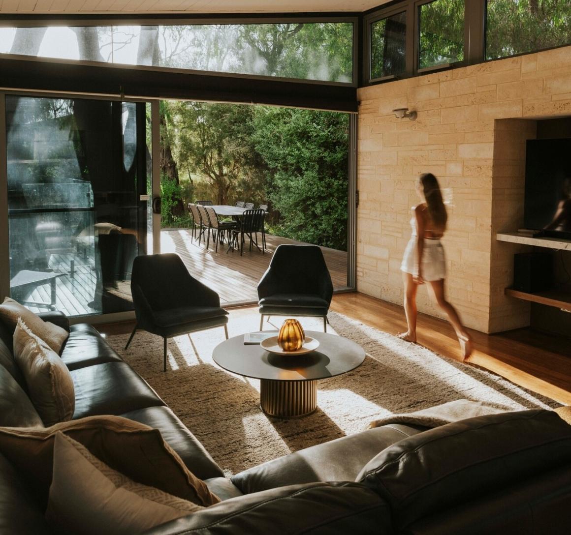 A woman walks through the living room at The Aqua Resort, showcasing the spacious interior and outdoor indoor design. One of the best accomodations in Busselton to stay at