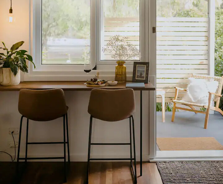 The breakfast eating nook at Lola By The Bay, one of the best places to stay in Busselton. Featuring two barstools at the window bench overlooking the outdoor patio.