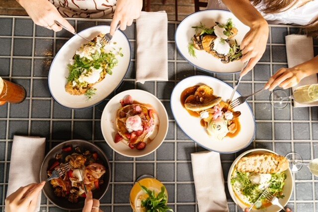A birds eye view of several plates of food on a table. People enjoying their food in Claremont town centre