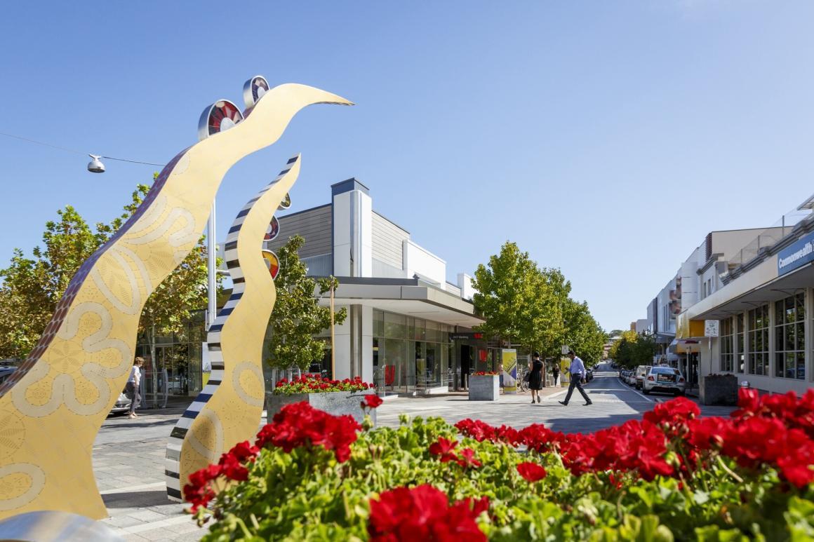 A photo of a gold modern art outdoor statue and red flowers at the Claremont town centre