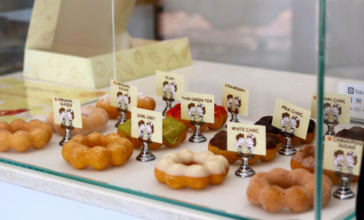 A display case at Mimochi showcasing all of their donut flavours with signs on their donuts
