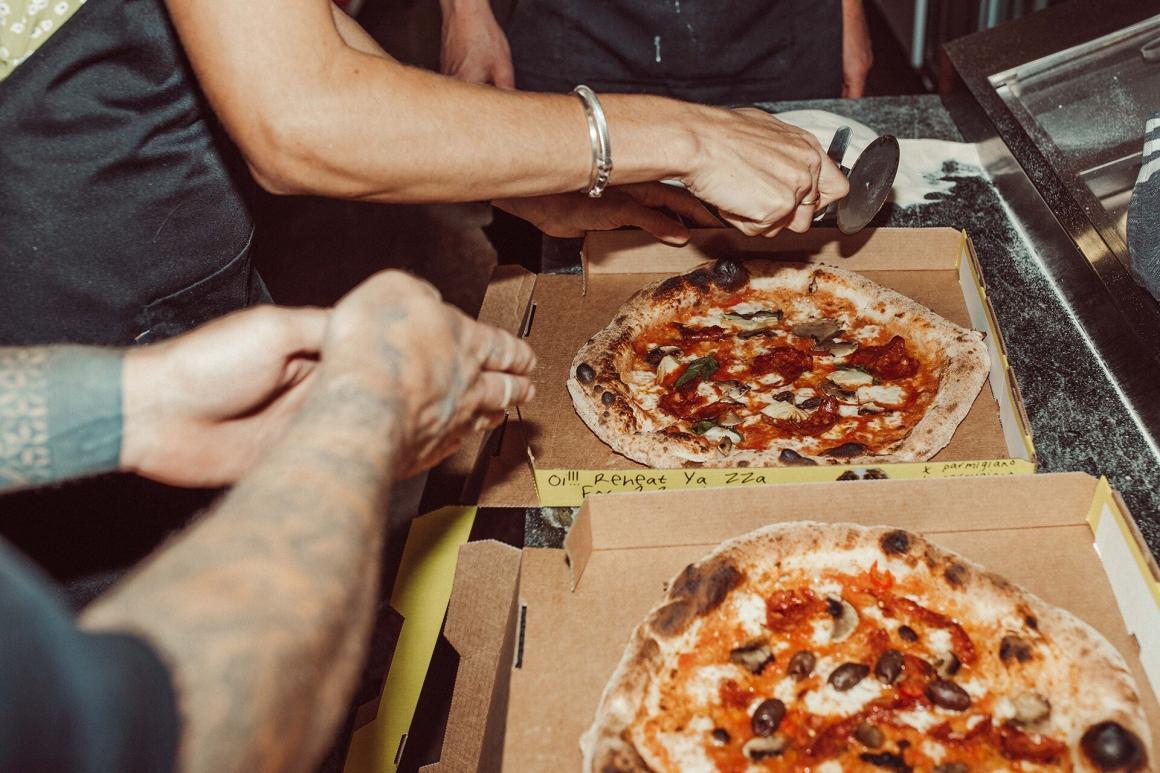 Two people cut pizzas they've just made