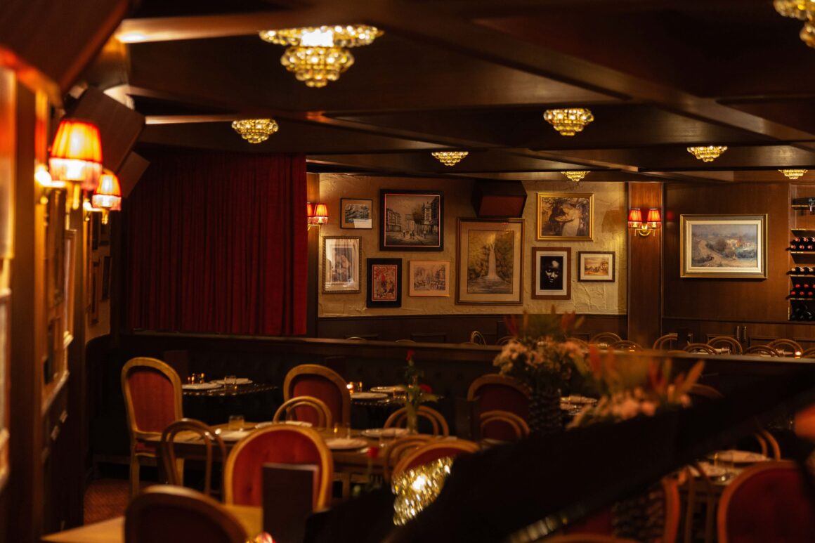 A wide angle shot of the interior of Ludo, showing the gallery wall, old school lounge styling, tables and chandeliers