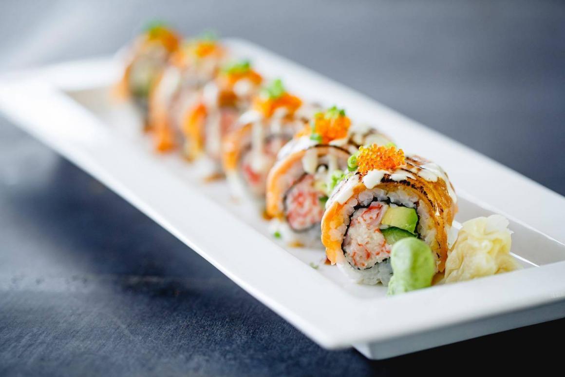A plate of sushi with wasabi and caviar on top sit on a grey table at Super Tetsudo
