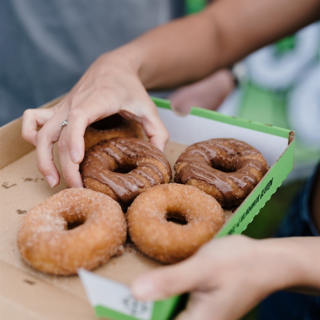 A hand placing a donut into a box of four