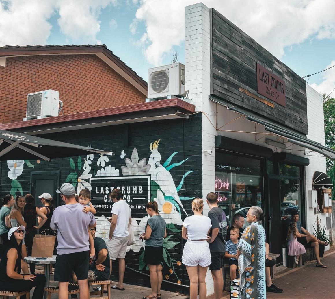 A street view of the outside of Last Crumb Cake Co store with a line out the door