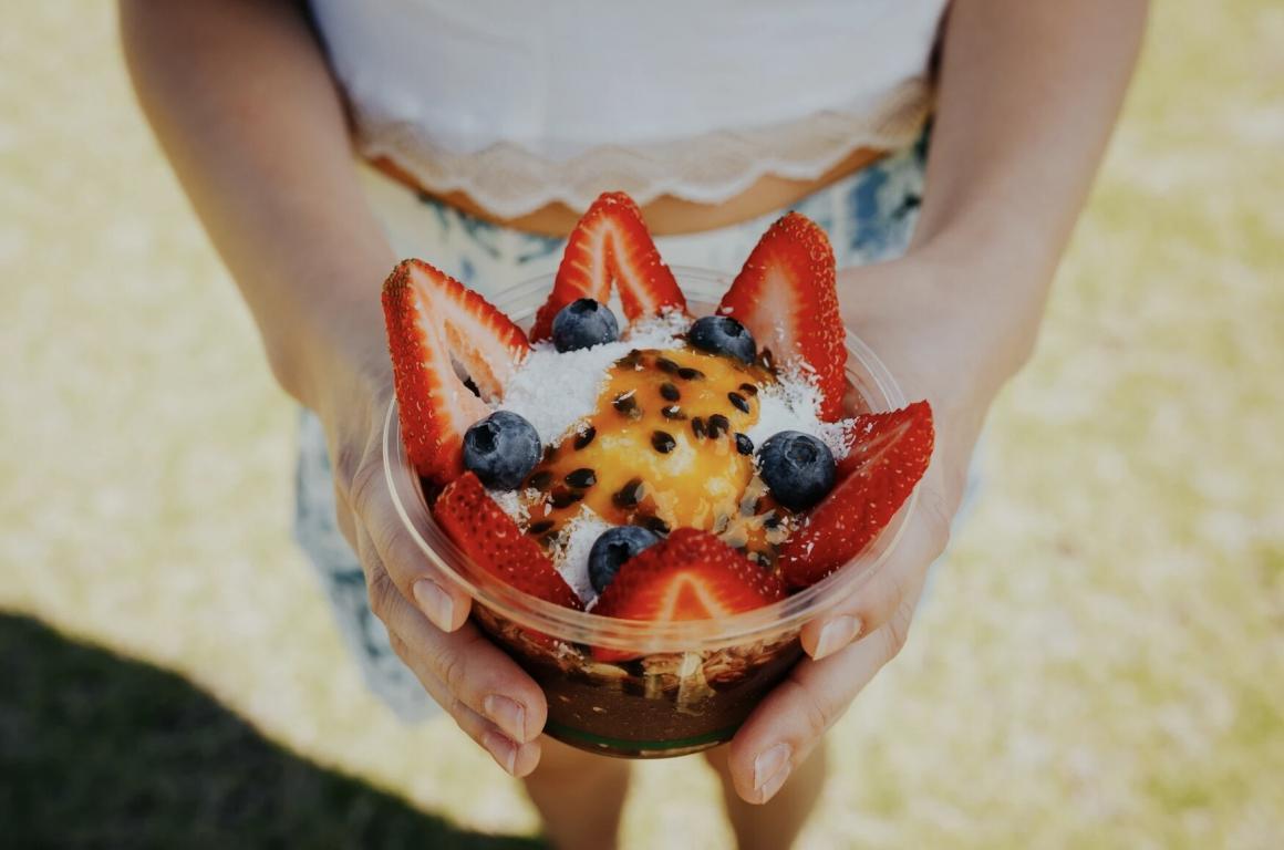 A woman holds an acai bowl, top down view