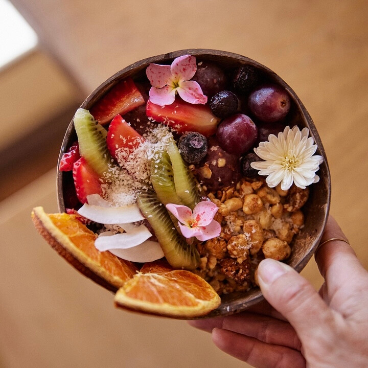 A woman holds an acai bowl, top down view