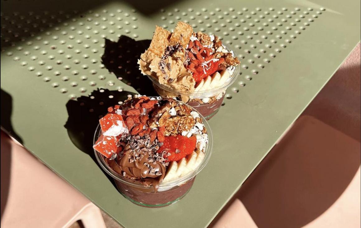 Two acai bowls sit on a green table at Oushk Palmyra