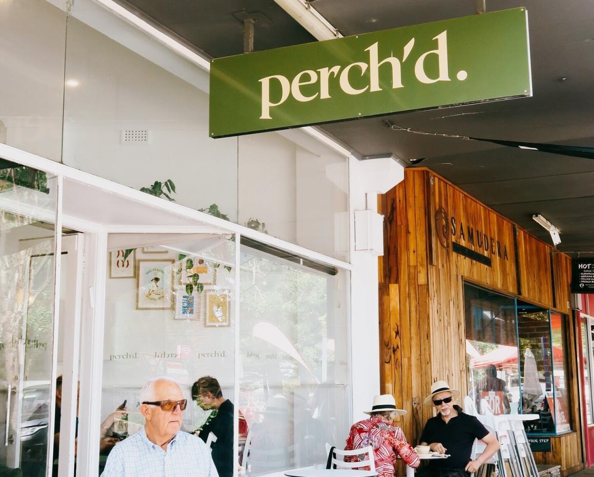 The outside dining area of Perch'd showing the sign and people eating