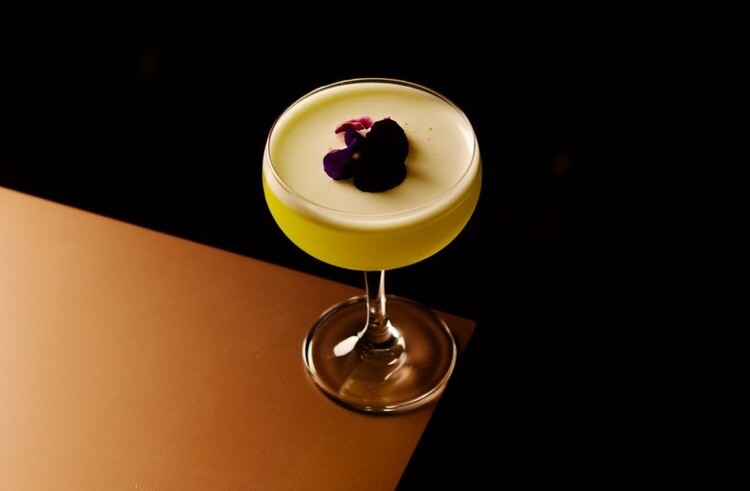 A cocktail sits on the edge of a bar