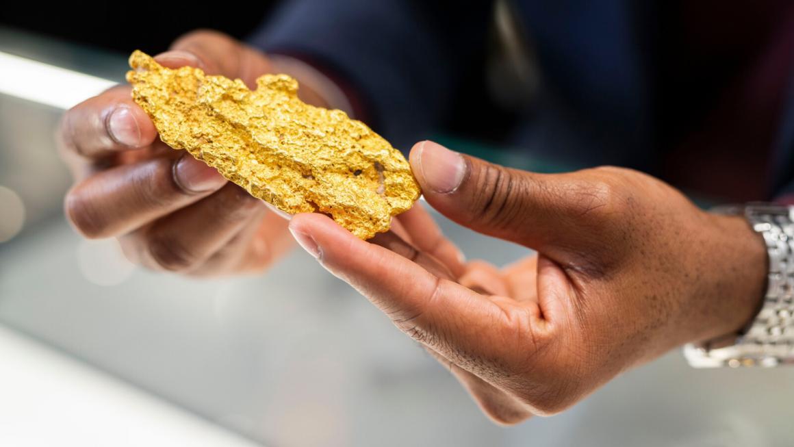 A woman holds a large gold nugget in her hands
