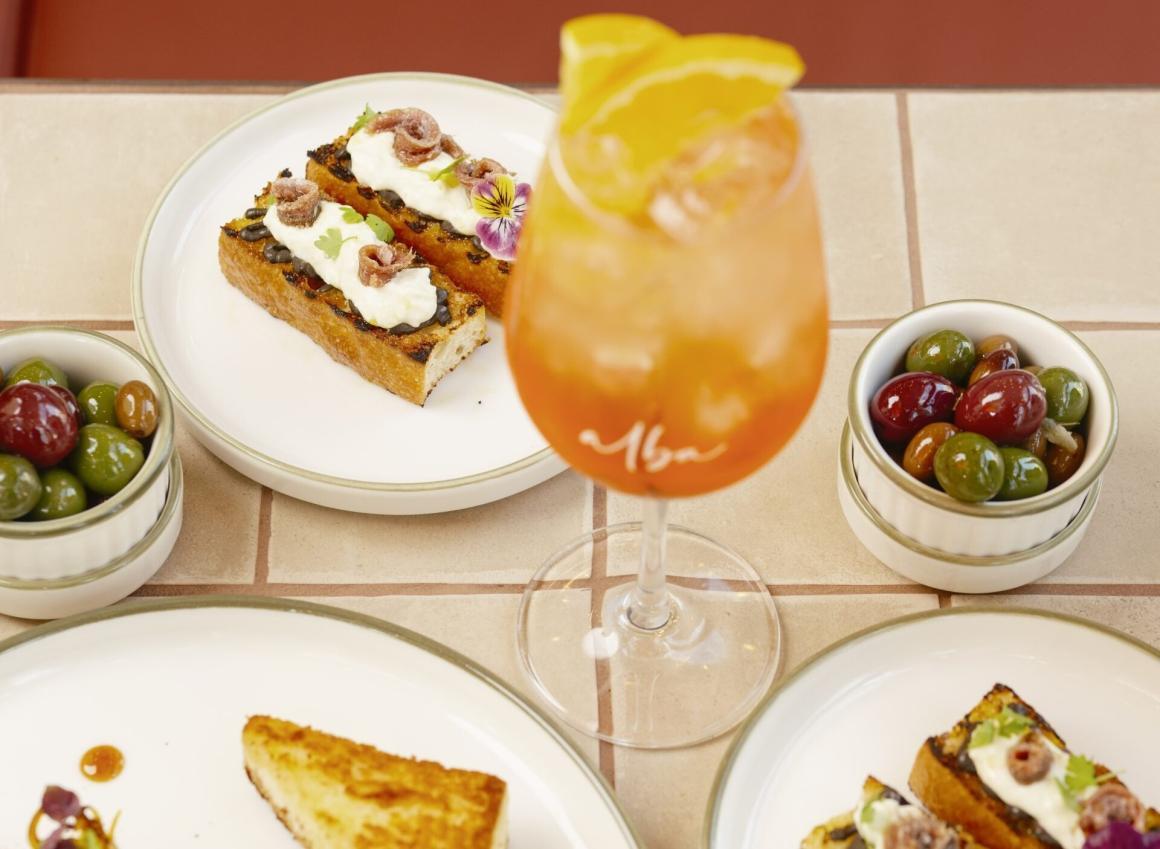 A cocktail with several entrees on a table at Alba