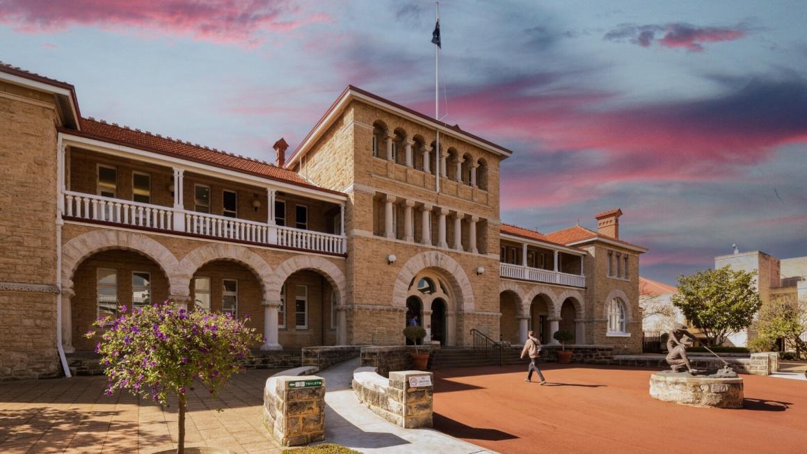 A wide shot of the outside of the Perth Mint with a sunset in the background