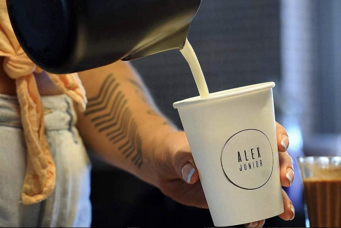 A woman pours milk into a matcha latte at Alex Junior in Perth