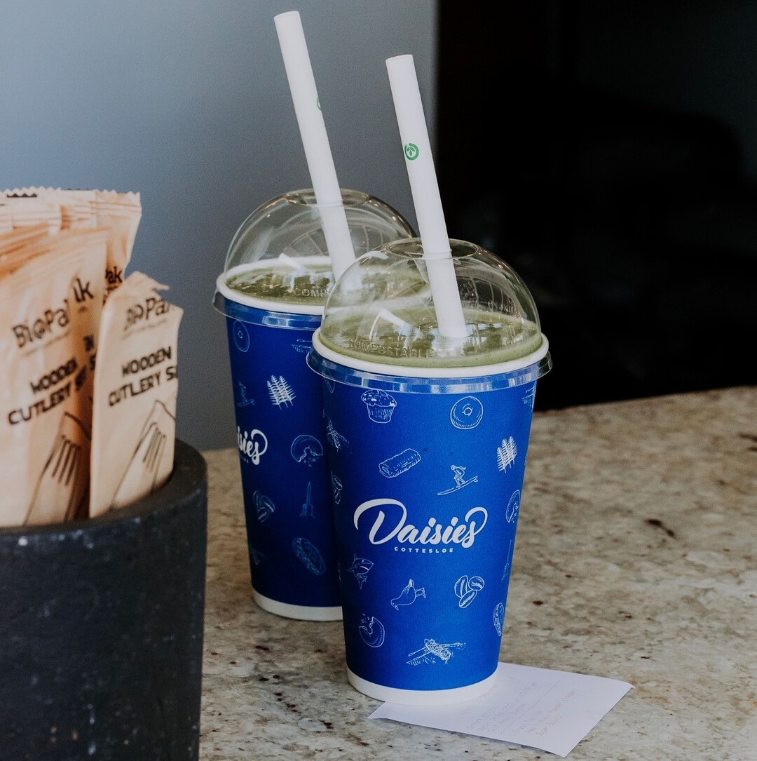Two matcha lattes in cups on the bench at Daisies in Perth