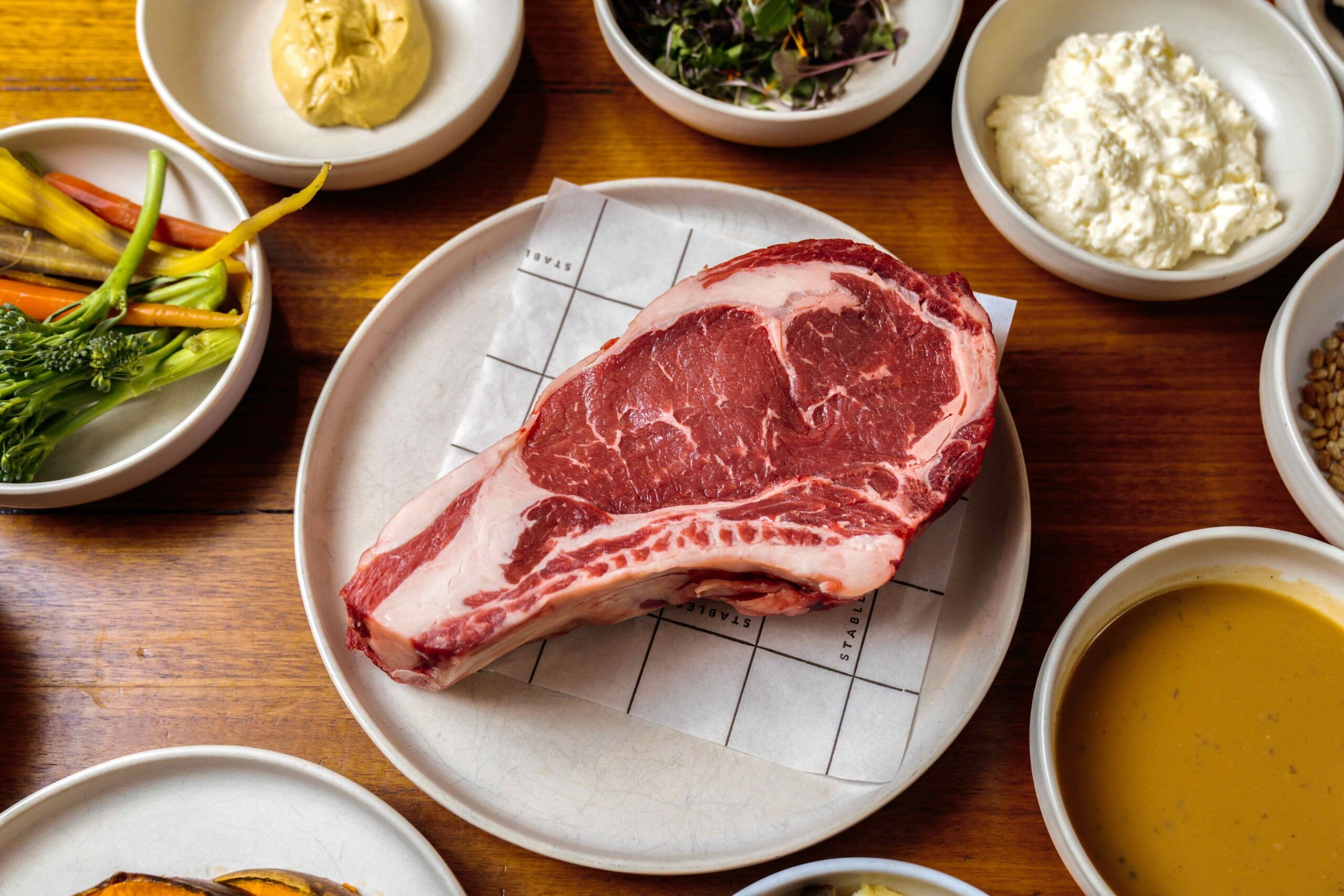 A cut of raw beef on a table at Stables steakhouse with other dishes