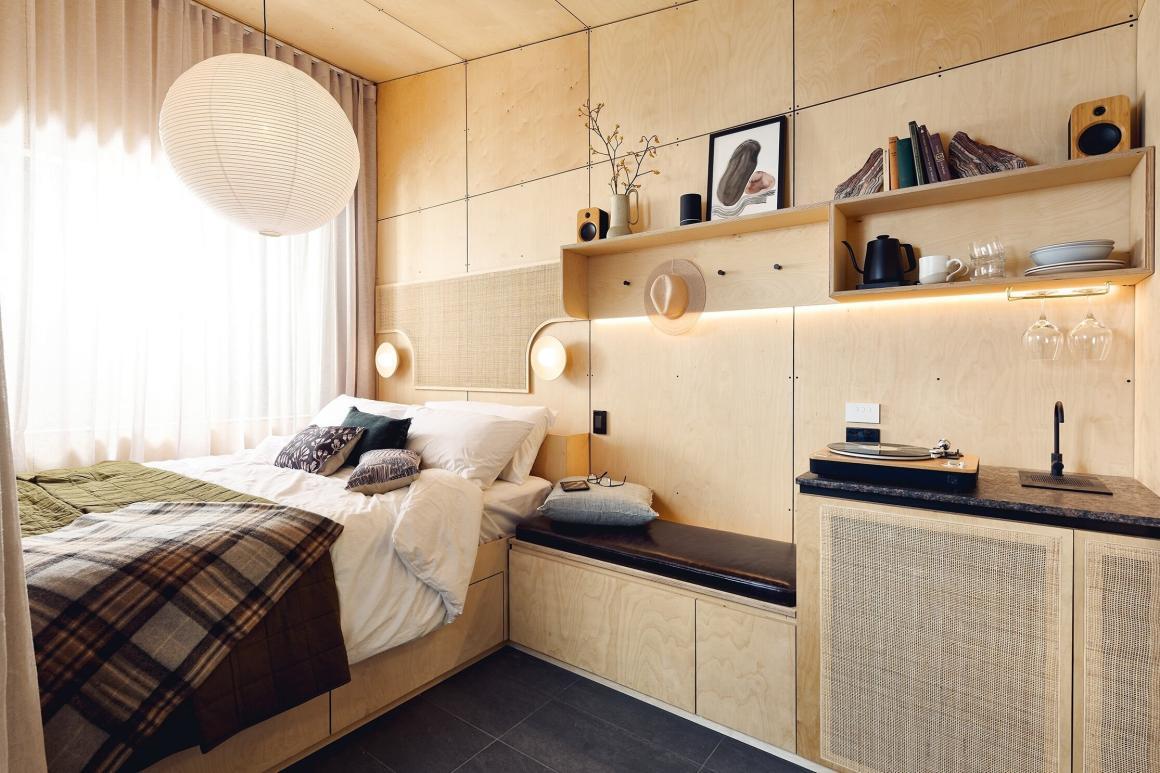 A wide angle view of the inside of the cabin at Southcampin Dunsborough. Showing the bed, shelving and storage