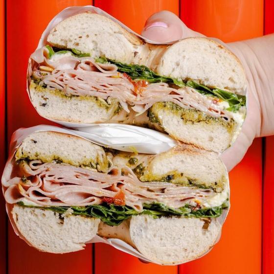 A person holds a bagel cut in half from Neighbourhood Bagel. One of Perth's best bagel spots