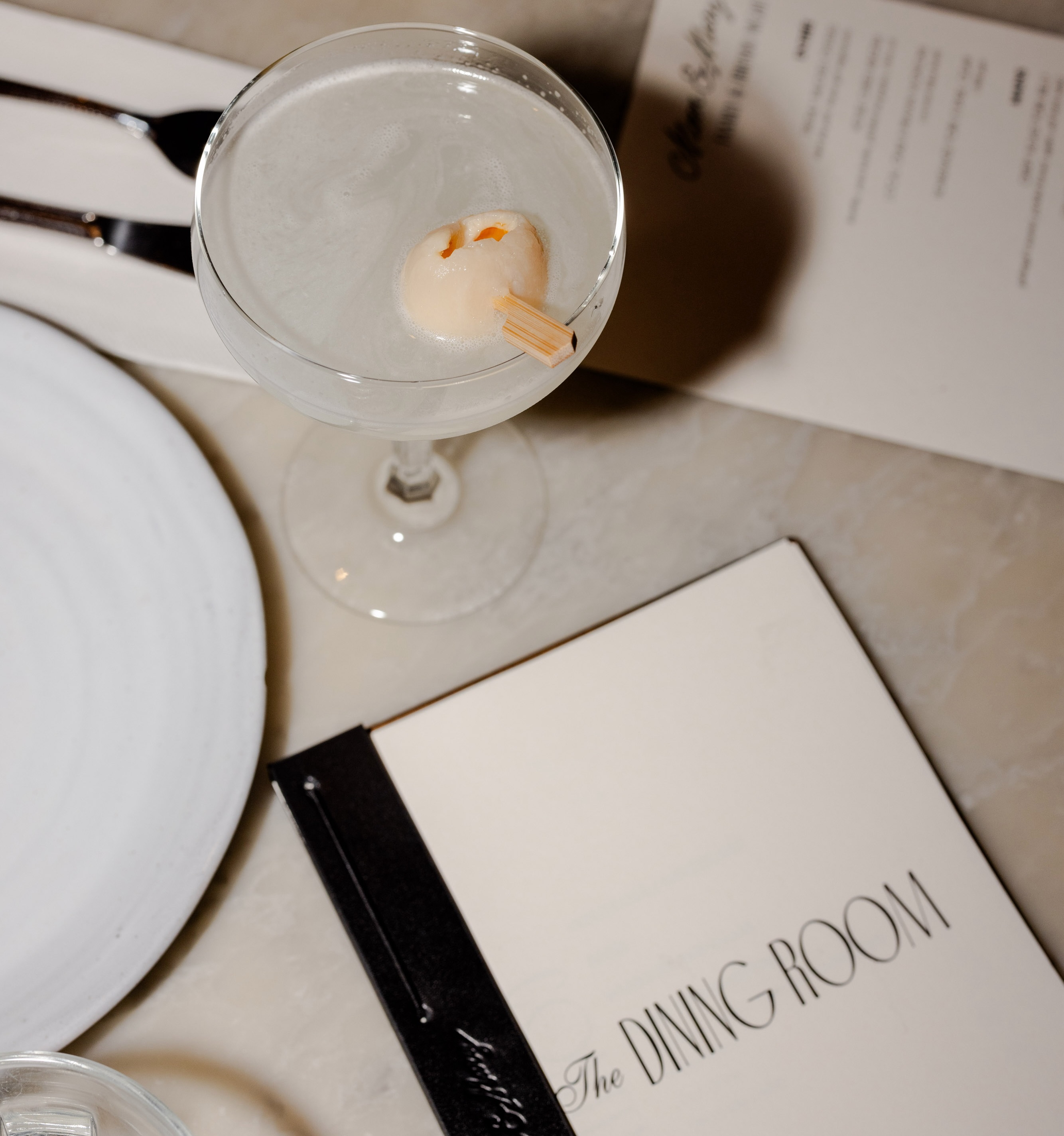 a table setting with a cocktail and menu in Moon & Mary's dining room