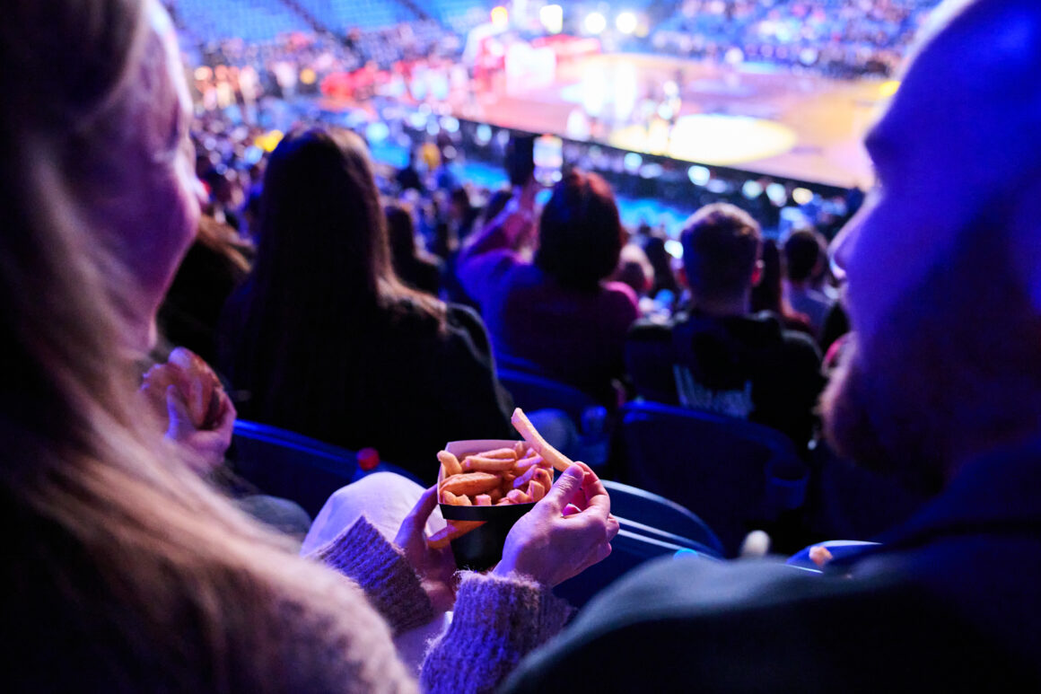 Two people sharing hot chips whilst watching a show at RAC Arena, highlighting their new click and collect food option