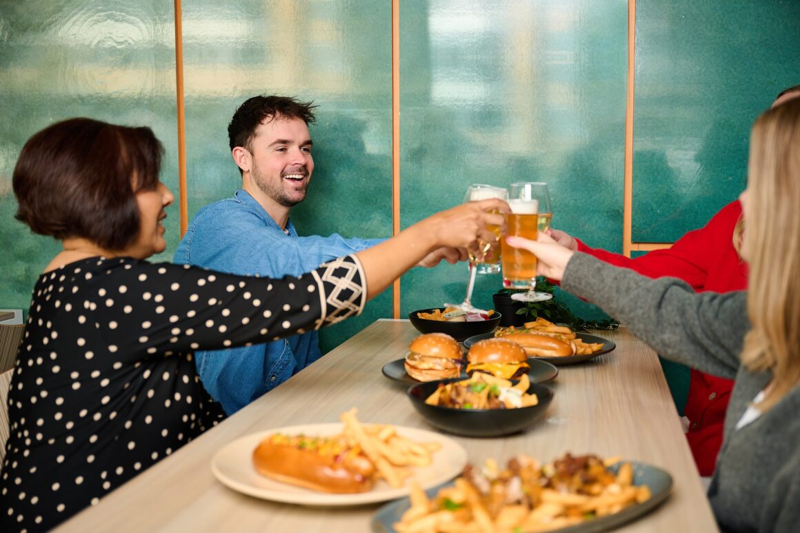 Four people sharing food and cheersing drinks at RAC Arena